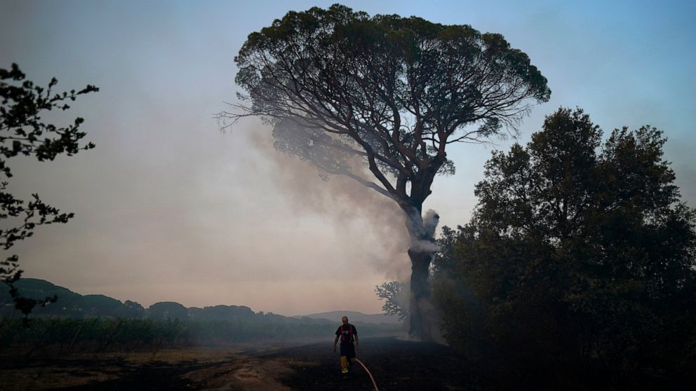 A fireman walks back to his truck after fighting a fire near Le Luc, southern France, Wednesday, Aug.18, 2021. A wildfire near the French Riviera killed at least two people and was burning out of control in the forests of the popular region, fueled b