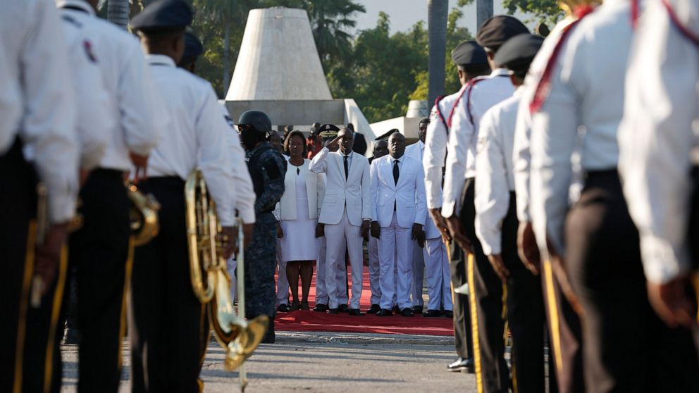 Accompanied by First Lady Martine Moise, center left, President Jovenel Moise salutes a police marching band before laying flowers to mark the anniversary of the death of Haitian revolution leader Jean Jacques Dessalines, at Champ de Mars, adjacent t