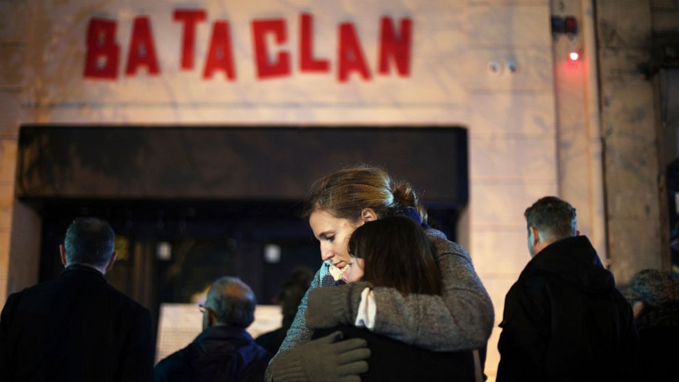 FILE - In this Nov. 13, 2016 file photo, women hug in front of the Bataclan concert hall in Paris. For more than two weeks, dozens of survivors from the Bataclan concert hall in Paris have testified in a specially designed courtroom about the Islamic