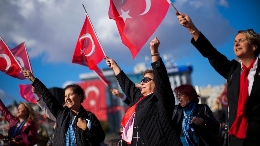 People wave Turkish flags as they listen a military music band performing at Taksim square in Istanbul, Turkey, Friday, Oct. 28, 2022. Turkish President Recep Tayyip Erdogan on Friday laid out his vision for Turkey in the next century, promising a ne