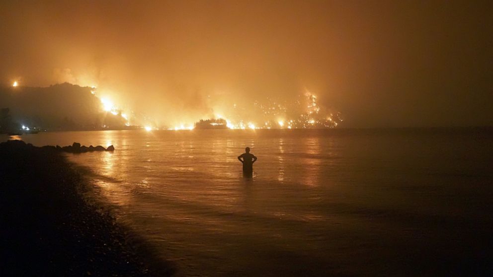 FILE - In this file photo dated Friday, Aug. 6, 2021, a man watches as wildfires approach Kochyli beach near Limni village on the island of Evia, about 160 kilometers (100 miles) north of Athens, Greece. A new massive United Nations science report is