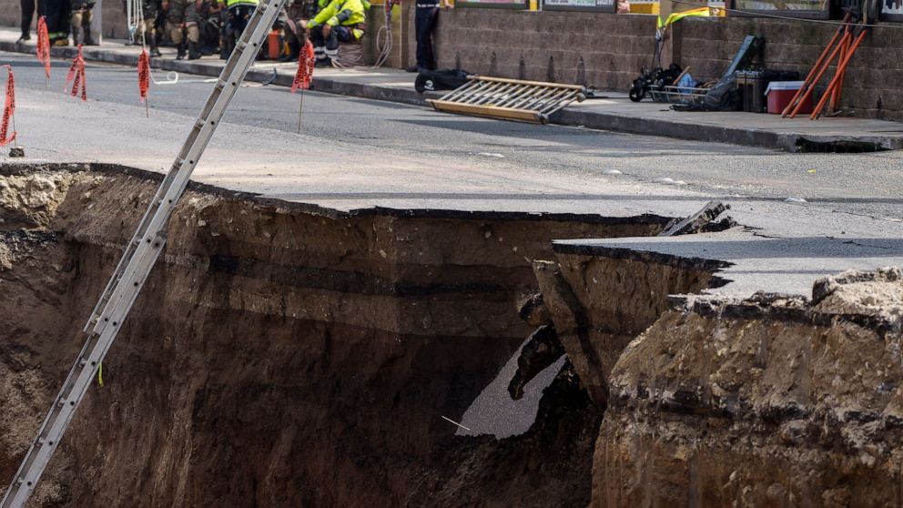 A block of asphalt falls off as rescuers prepare to resume search efforts at a sinkhole in Villa Nueva, Guatemala, Tuesday, Sept. 27, 2022. Search efforts were underway for a mother and daughter who disappeared when their vehicle was swallowed by the