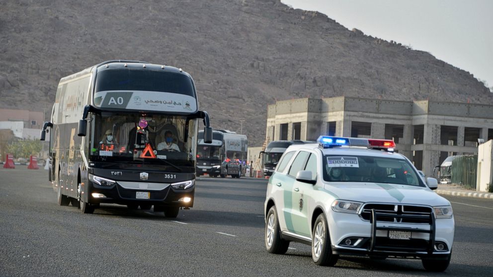 A police vehicle escorts a pilgrim convoy as they move towards the Grand Mosque ahead of the Hajj pilgrimage in the Muslim holy city of Mecca, Saudi Arabia, Wednesday, July 29, 2020. During the first rites of hajj, Muslims circle the Kaaba counter-cl