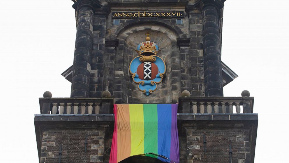 A large rainbow flag flies from the bell tower of Wester Church to mark the 20th anniversary of the first legalized same-sex marriage in Amsterdam, Netherlands, Thursday, April 1, 2021. Twenty years ago, the mayor of Amsterdam married four couples in