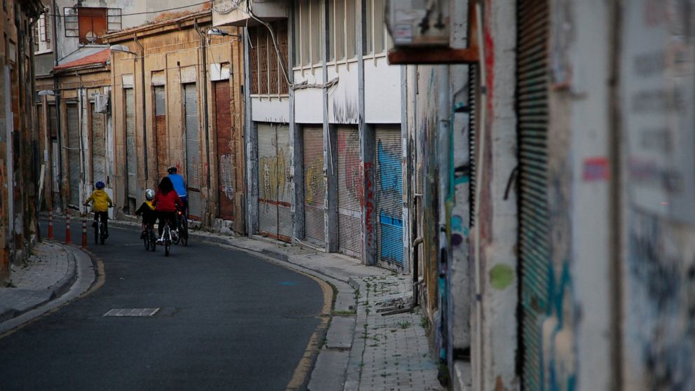 A family ride their bicycles during the lockdown measures by government to prevent the spread of coronavirus pandemic in the medieval core in central capital Nicosia Wednesday, April 22, 2020. Cyprus President Nicos Anastasiades said the island natio