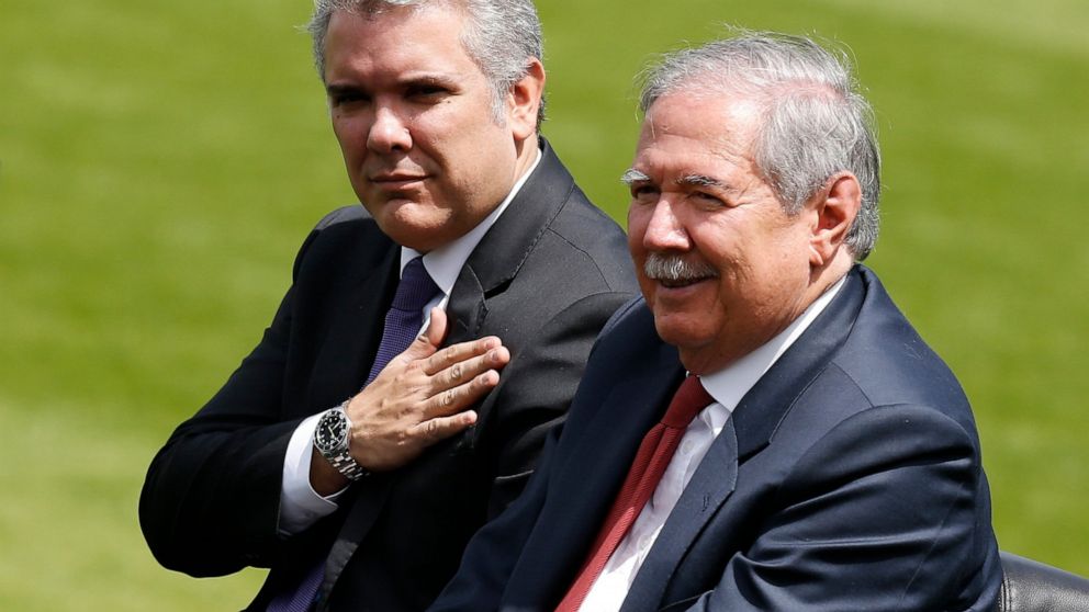 FILE - In this Dec. 17, 2018 file photo, Colombia's President Ivan Duque places his hand over his chest as he reviews the troops with Defense Minister Guillermo Botero during a swearing-in ceremony for the new military and police commanders, in Bogot