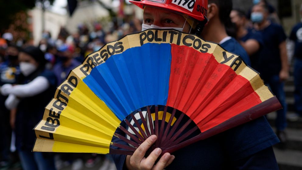 A woman holds a paper fan marked with a message that reads in Spanish: "Freedom for political prisoners now", during a gathering by opposition members to mark Youth Day, in Caracas, Venezuela, Saturday, Feb. 12, 2022. The annual holiday commemorates 