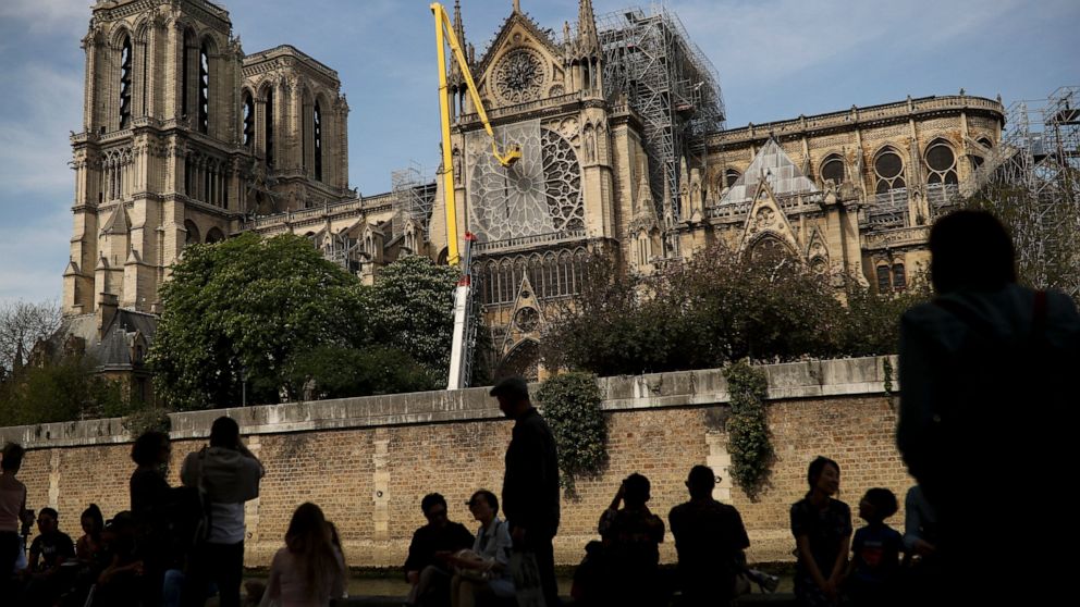 FILE - In this Sunday, April 21, 2019 file photo, workers fix a net to cover one of the iconic stained glass windows of the Notre Dame Cathedral in Paris. Notre Dame cathedral officials have said Friday, March 5, 2021 the first eight oaks destined to