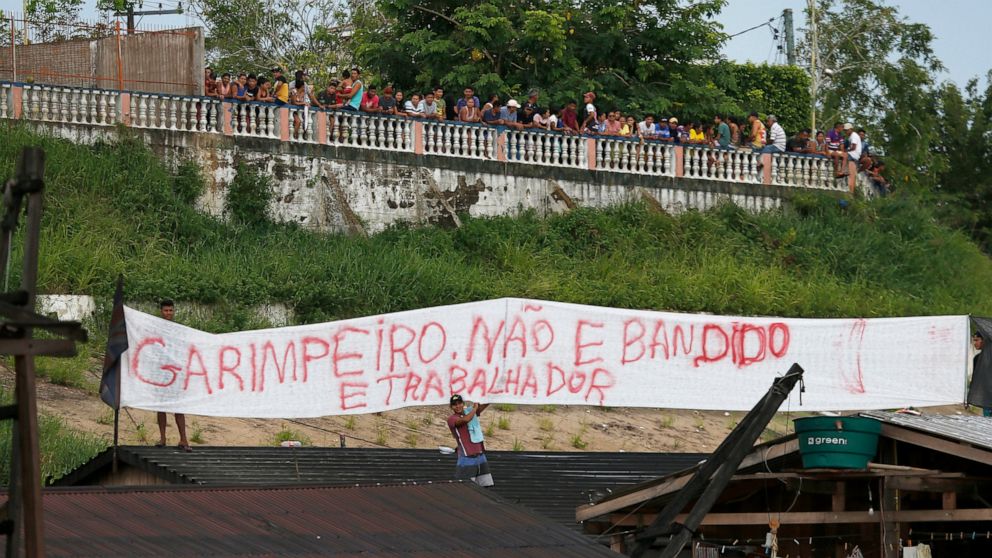 Illegal miners display a banner that reads in Portuguese "Gold miners are not bandits, They are workers," after more than 60 dredging barges were set on fire by officers of the Brazilian Institute of the Environment and Renewable Natural Resources, I