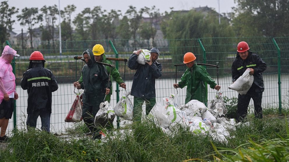 In this photo released by Xinhua News Agency, workers carry sandbags to reinforce a riverbank to prevent the river back flow caused by the approaching typhoon Muifa in Jiashan County of Jiaxing City, east China's Zhejiang Province, Wednesday, Sept. 1