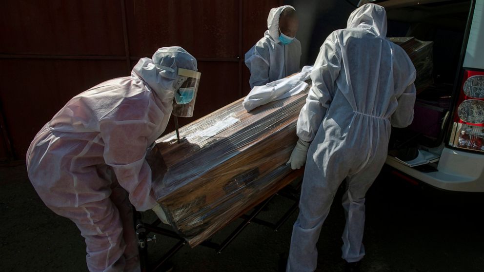 Funeral home workers in protective suits carry the coffin of a woman who died from COVID-19 into a hearse in Katlehong, near Johannesburg, South Africa, Tuesday, July 21, 2020. South Africa, last Saturday became one of the top five worst-hit countrie