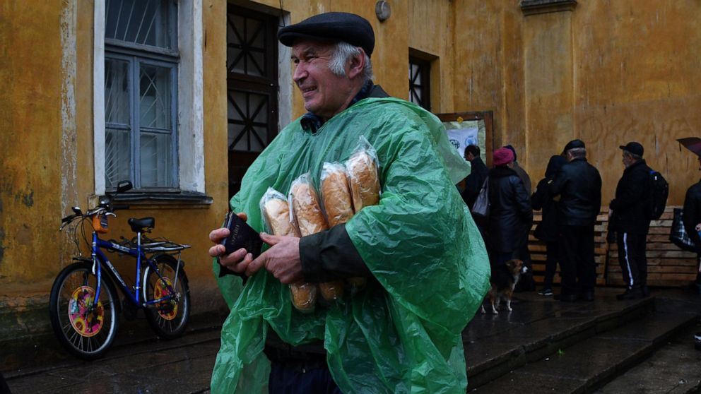 A man carries Ukrainian passport and bread after receiving it at humanitarian aid center in Kramatorsk, Ukraine, Wednesday, Oct. 26, 2022. (AP Photo/Andriy Andriyenko)