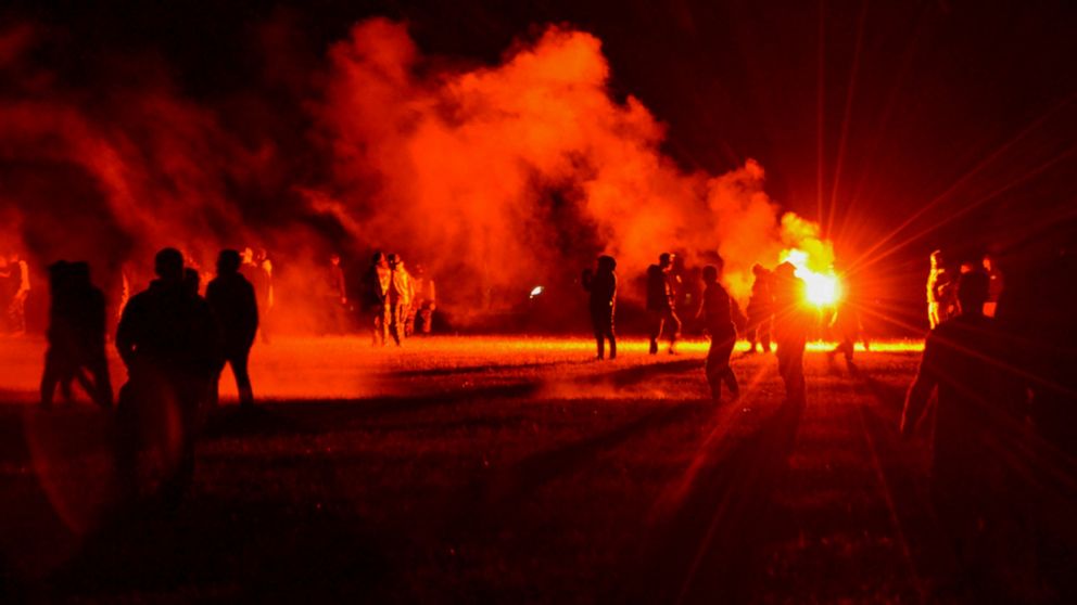 Youths stand in a field during clashes as police tried to break up an unauthorized rave party near Redon, Brittany, Friday June 18, 2021. Police repeatedly fired tear gas and charged clusters of violent partiers who hurled metal balls, gasoline bombs