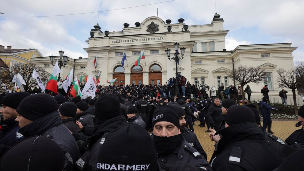 Police officers line up as they try to keep protesters away from the Bulgarian Parliament building in Sofia, Wednesday, Jan. 12, 2022. Protesters opposing COVID-19 restrictions in Bulgaria have clashed with police as they were trying to storm the Par