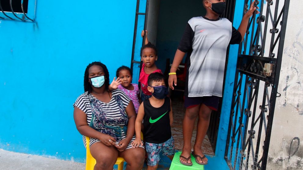 FILE - In this April 14, 2020 file photo, a family waits outside their home to receive food handouts from the local government, in the Cristo del Consuelo neighborhood of Guayaquil, Ecuador. In March and April, Guayaquil was a pandemic hellscape of m