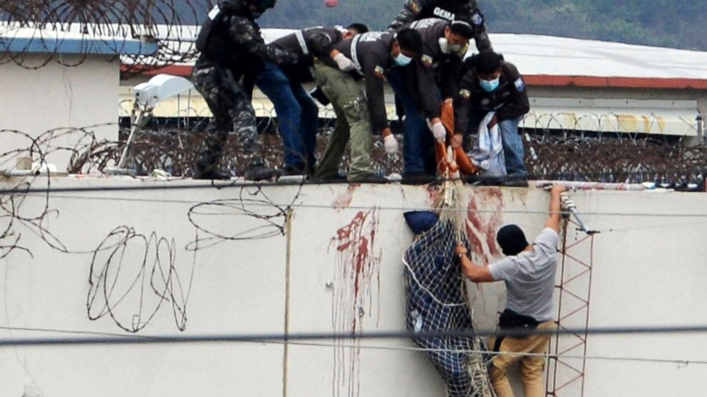 Police lower the body of a prisoner from the roof of the Litoral penitentiary the morning after riots broke out inside the jail in Guayaquil, Ecuador, Saturday, Nov. 13, 2021. (AP Photo/Jose Sanchez)