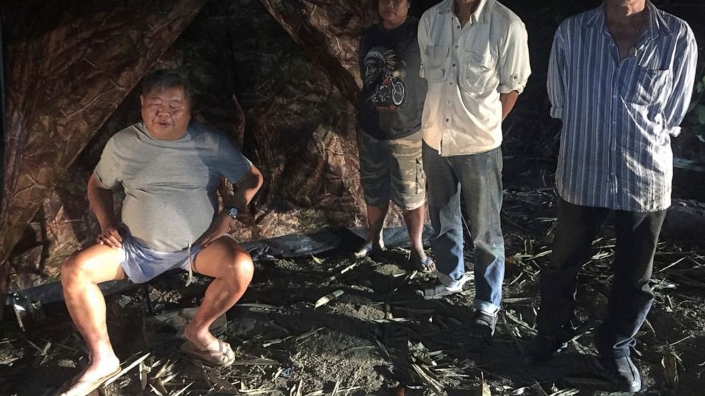 File - In this photo released by the Thailand Department of National Parks, Wildlife and Plant Conservation, the president of Thailand's largest construction company Premchai Karnasuta, 63, left, is seen with a group while being detained in the Thung