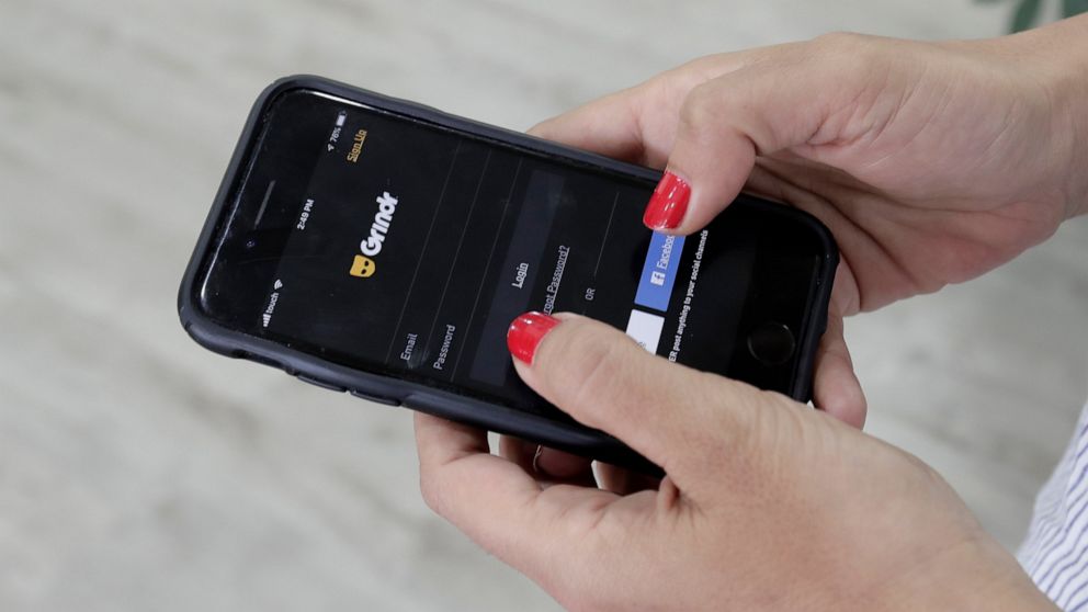 FILE - In this Wednesday, May 29, 2019 file photo, a woman checks the Grindr app on her mobile phone in Beirut, Lebanon. Dating apps including Grindr, OkCupid and Tinder leak personal information to advertising tech companies in possible violation of