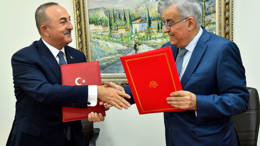 In this photo released by Lebanon's official government photographer Dalati Nohra, Turkey's Foreign Minister Mevlut Cavusoglu, left, shakes hands with his Lebanese counterpart Abdallah Bou Habib, after they sign agreements between the two countries, 