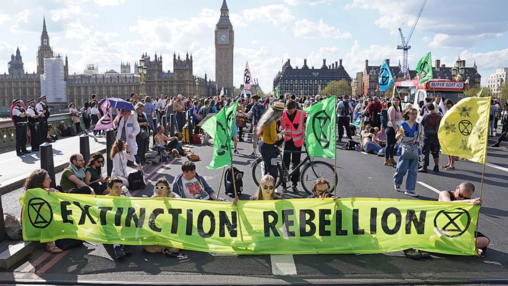 Demonstrators take part in an Extinction Rebellion protest on Westminster Bridge in London, Friday, April 15, 2022. Climate-change protesters have snarled traffic by blocking four London bridges. Cars and red double-decker buses backed up along roads