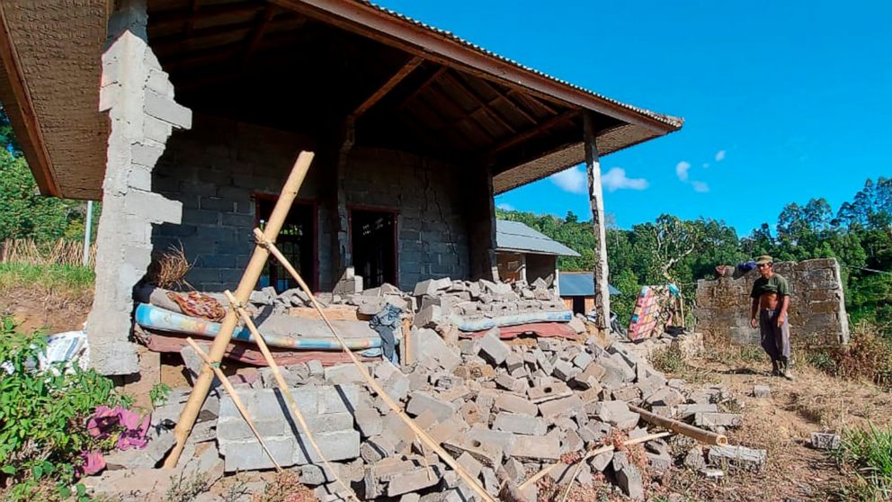 A man stands near his house damaged by an earthquake in Karangasem on the island of Bali, Indonesia, Saturday, Oct. 16, 2021. A few people were killed and another several were injured when a moderately strong earthquake and an aftershock hit the isla