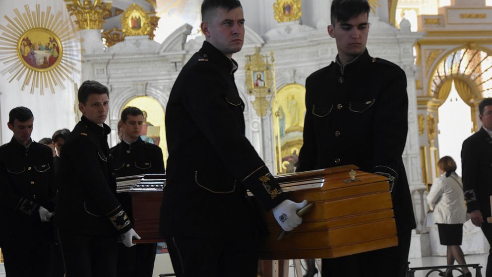 Men carry coffins during a funeral ceremony for Kira Glodan, three-month-old, her mother Valerya Glodan, 28, and grandmother Lyudmila Yavkina, 54, killed in their apartment by shelling, at the Transfiguration Cathedral in Odessa, Ukraine, Wednesday, 