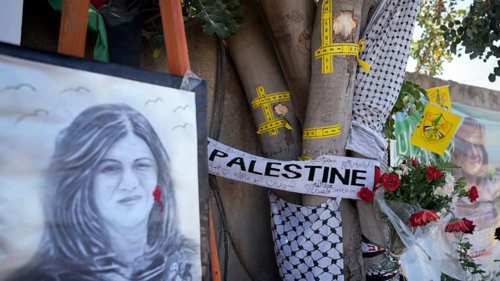 Yellow tape marks bullet holes on a tree and a portrait and flowers create a makeshift memorial at the site where Palestinian-American Al-Jazeera journalist Shireen Abu Akleh was shot and killed in the West Bank city of Jenin, Thursday,, May 19, 2022