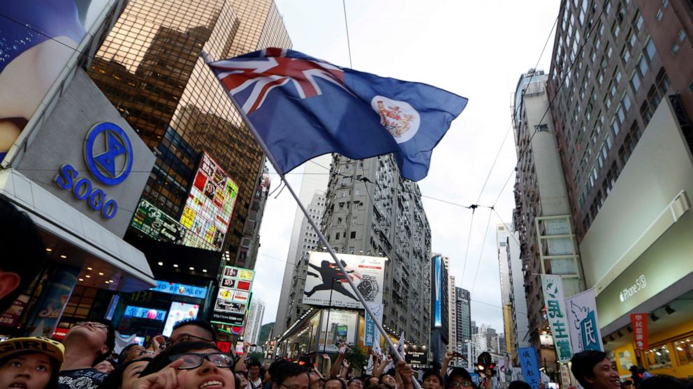 FILE - A protester waves a Hong Kong colonial flag as people march during an annual protest in downtown Hong Kong, Tuesday, July 1, 2014. Hong Kong is preparing to introduce new middle school textbooks that will deny the Chinese territory was ever a 