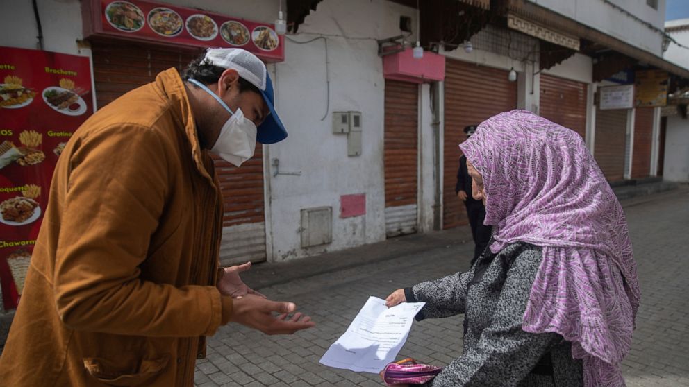 A member of security forces inspects a permit allowing a woman to leave her home, after a health state of emergency was declared and members of the public ordered to a home confinement, in Rabat, Morocco, Sunday, March 22, 2020. For some people the C