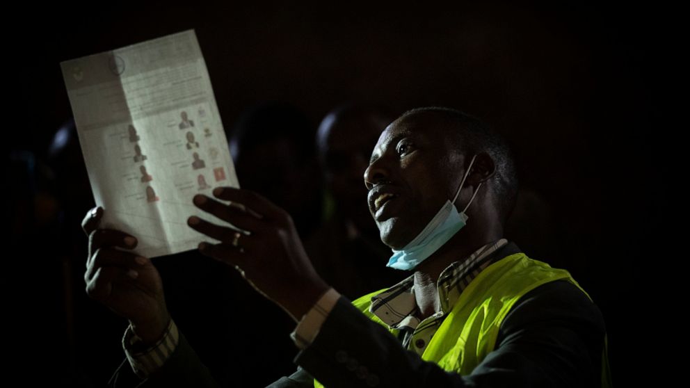 An election official holds up ballots for other officials and party agents to see, as they start to count votes at a polling station in Olepolos Primary School, in Kajiado County, Kenya Tuesday, Aug. 9, 2022. Polls opened Tuesday in Kenya's unusual p