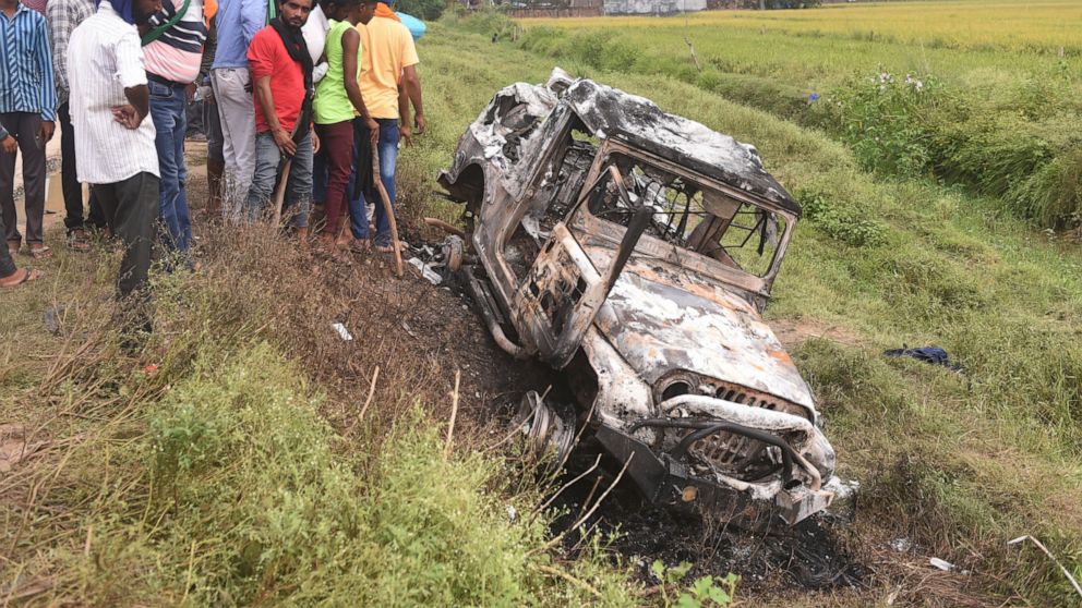 Villagers watch a burnt car which run over and killed farmers on Sunday, at Tikonia village in Lakhimpur Kheri, Uttar Pradesh state, India, Monday, Oct. 4, 2021. Indian authorities suspended internet services and barred political leaders from enterin