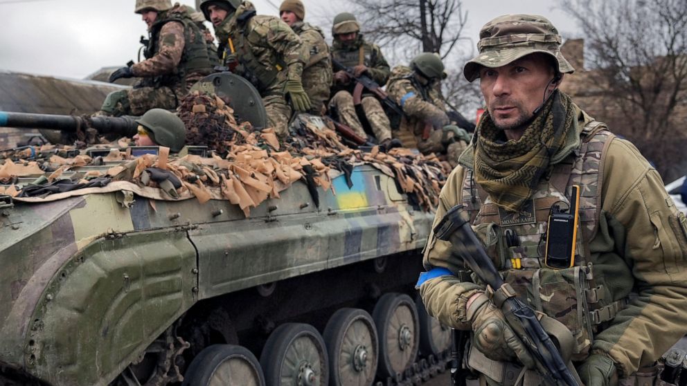 FILE - A Ukrainian serviceman walks next to a fighting vehicle, outside Kyiv, Ukraine, Saturday, April 2, 2022. As he begins a second term as France's president, Emmanuel Macron has given the green light for the delivery of artillery pieces to Ukrain
