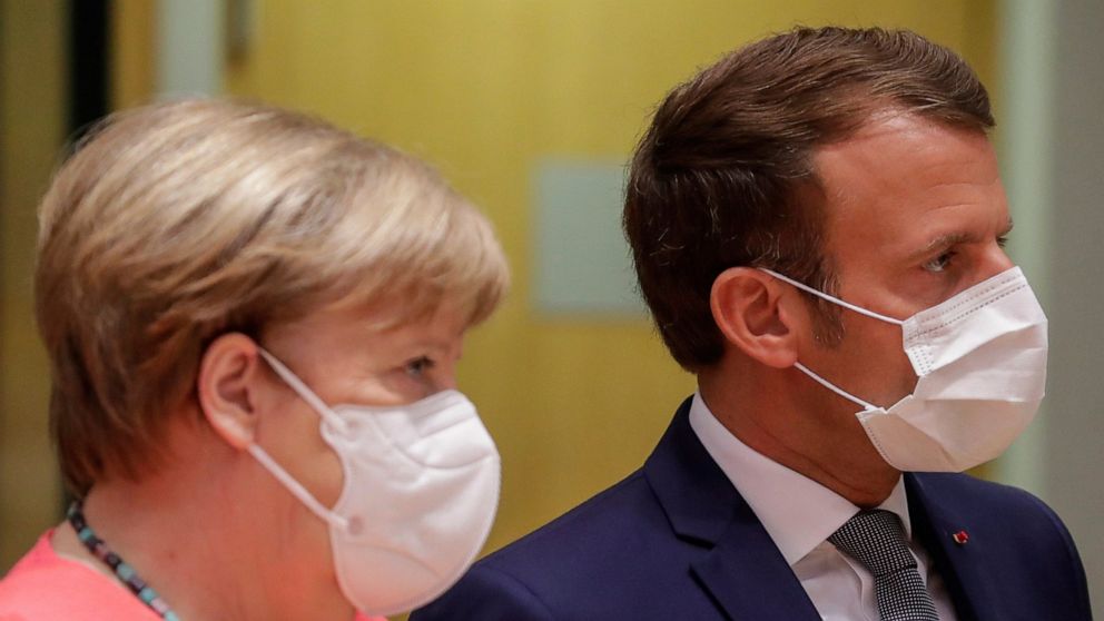 German Chancellor Angela Merkel, left, and French President Emmanuel Macron arrive for a round table meeting at an EU summit in Brussels, Friday, July 17, 2020. Leaders from 27 European Union nations meet face-to-face on Friday for the first time sin
