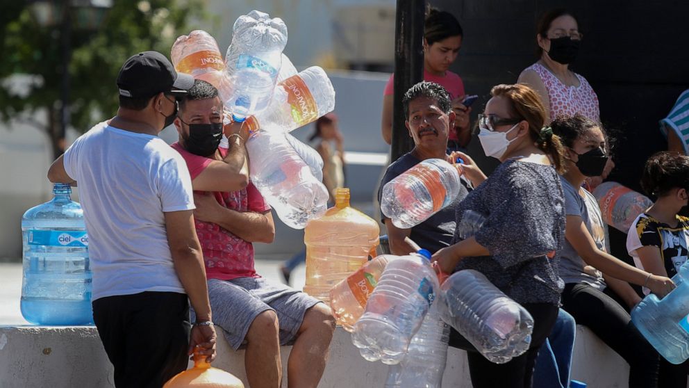 Neighbors wait with plastic containers in hand to collect water at a public collection point in Monterrey, Mexico, Monday, June 20, 2022. Local authorities began restricting water supplies in March, as a combination of an intense drought, poor planni