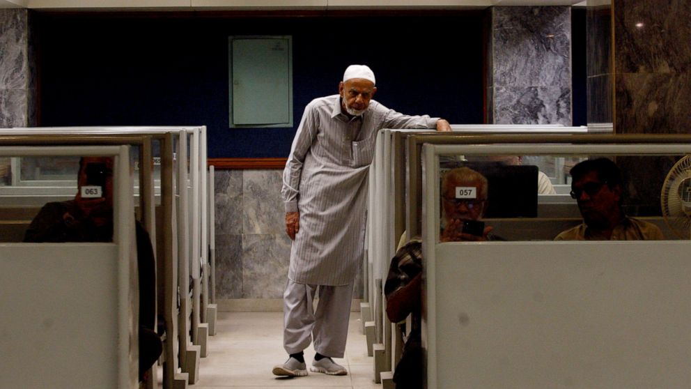 An investor monitors a stock index on a screen while brokers work at their desks at the Pakistan Stock Exchange, which responded positively after the news of an International Monetary Fund bailout package, in Karachi, Pakistan, Thursday, July 14, 202
