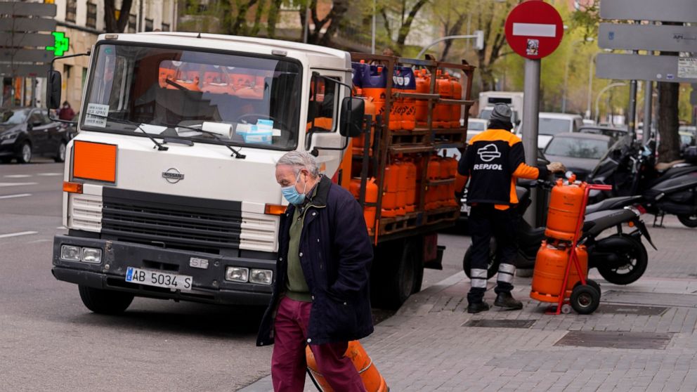 A man wheels a butane gas bottle he just bought from a delivery truck in Madrid, Spain, Monday, March 28, 2022. Spain's government is readying a package of emergency economic measures worth 6 billion euros (6.6 billion dollars) in direct aid and tax 