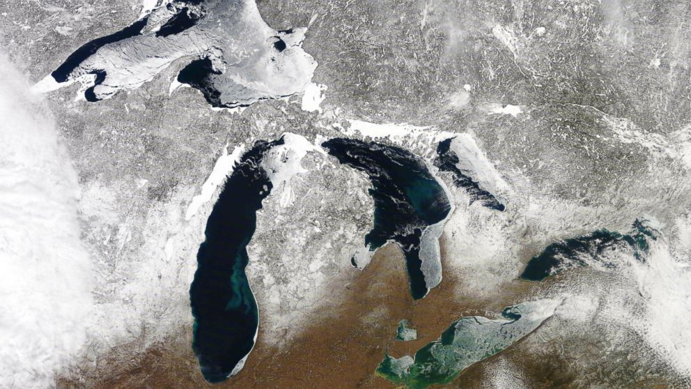 In this March 12, 2019 satellite photo provided by NOAA, shows the Great Lakes in various degrees of snow and ice. A scientific report says the Great Lakes region is warming faster than the rest of the U.S., which likely will bring more flooding and 