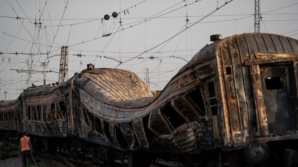 FILE - A railway worker stands next to heavily damaged train after a Russian attack on a train station yesterday during Ukraine's Independence Day in the village Chaplyne, Ukraine, on Aug. 25, 2022. The rail service has had some 300 workers killed an