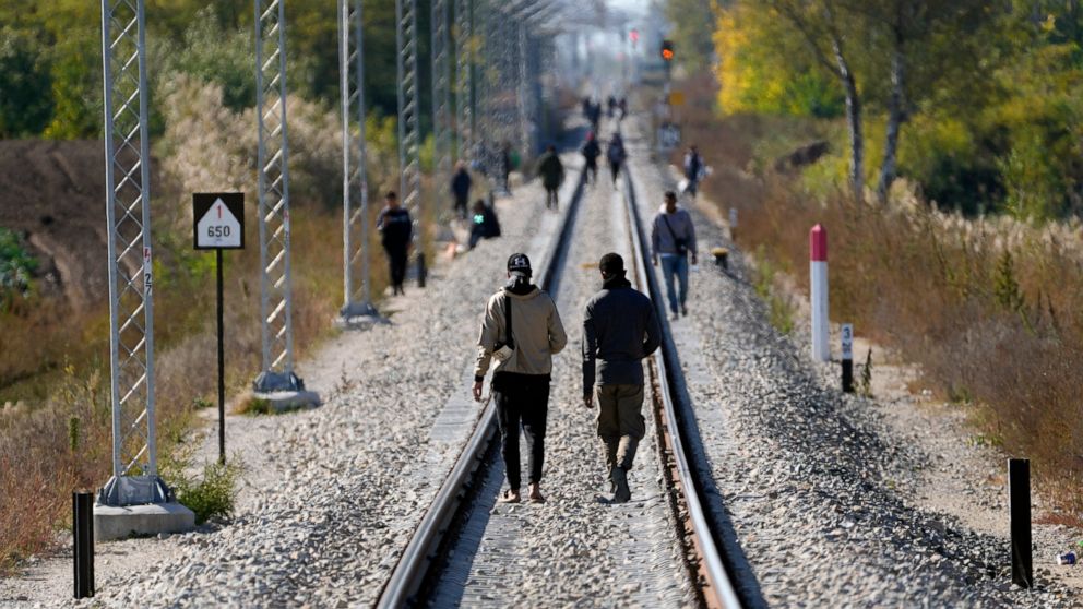 Migrants walk on the railway tracks near a border line between Serbia and Hungary, near village of Horgos, Serbia, Thursday, Oct. 20, 2022. Located at the heart of the so-called Balkan route, Serbia recently has seen a sharp rise in arrivals of migra