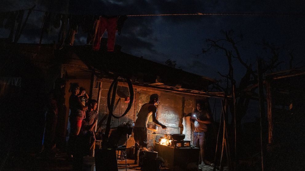 FILE - The Ramos family cooks dinner over a fire outside their storm-damaged home a week after Hurricane Ian knocked out electricity to the entire island, in La Coloma, Pinar del Rio province, Cuba, Oct. 5, 2022. Cuba's energy crisis has once again t