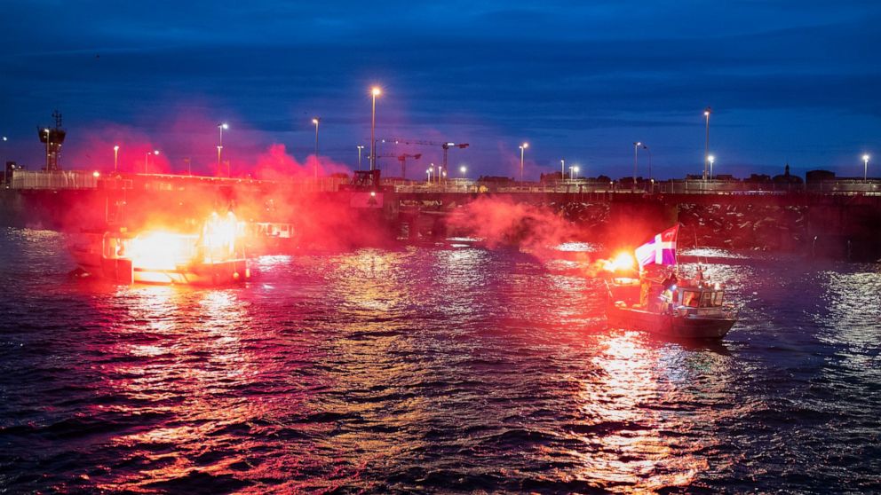 French fishermen light flares as they block the entrance to the port of Saint-Malo, western France, Friday, Nov. 26, 2021. French fishing crews are threatening to block French ports and traffic under the English Channel on Friday to disrupt the flow 