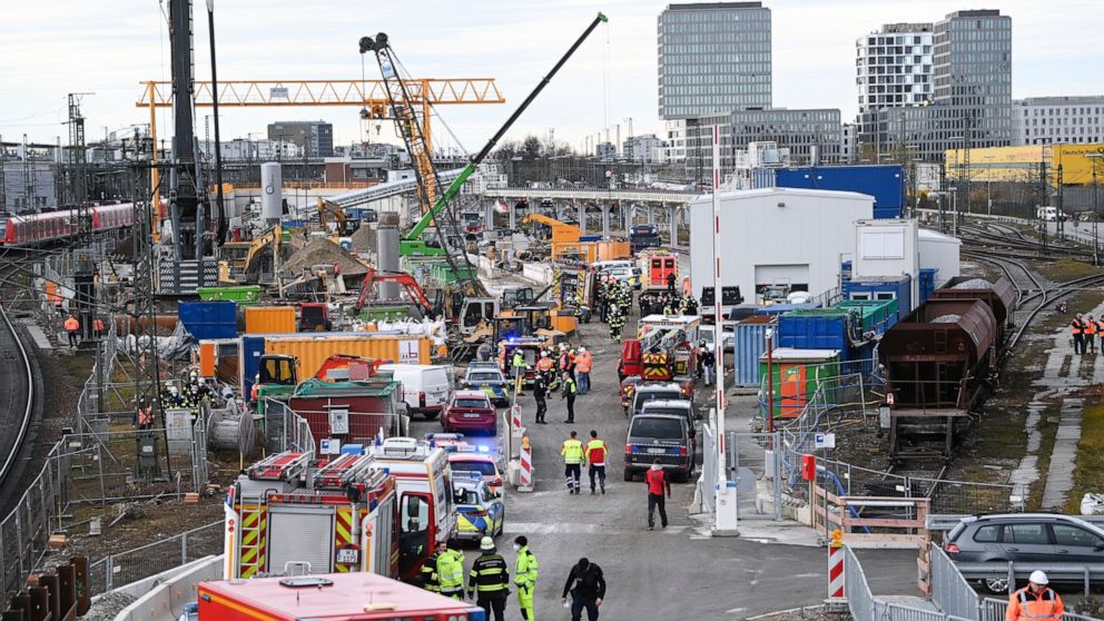 Firefighters, police officers and railway employees stand on a railway site in Munich, Germany, Wednesday, Dec. 1, 2021. Police in Germany say three people have been injured including seriously in an explosion at a construction site next to a busy ra