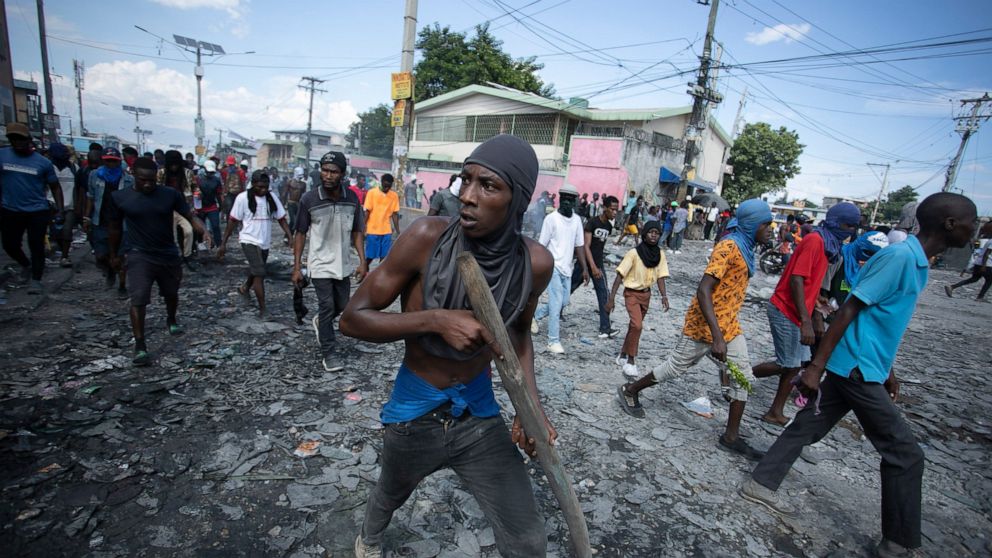 FILE - A protester carries a piece of wood simulating a weapon during a protest demanding the resignation of Prime Minister Ariel Henry, in the Petion-Ville area of Port-au-Prince, Haiti, Oct. 3, 2022. Haiti's government has agreed to request the hel