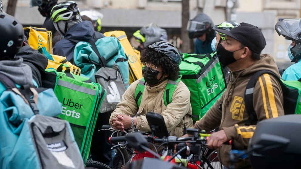 Delivery riders gather to protest outside the Spanish parliament in Madrid, Wednesday March 3, 2021. Food delivery workers have staged protests across Spain, urging the government to approve a promised law granting them the right to choose between be