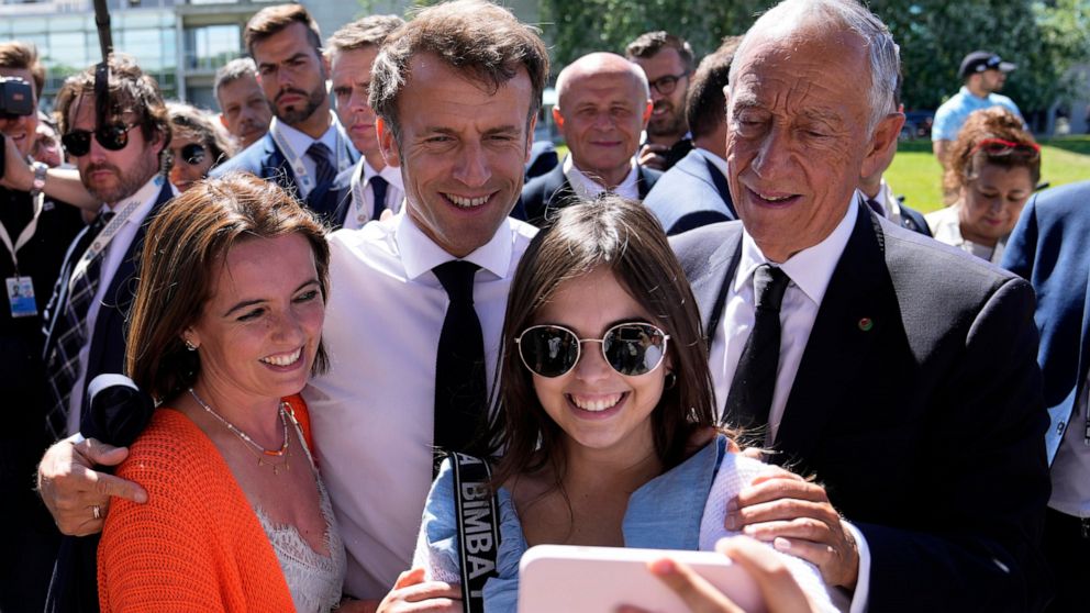 French President Emmanuel Macron and his Portuguese counterpart Marcelo Rebelo de Sousa, right, pose for a photo with well-wishers outside the venue hosting the United Nations Ocean Conference in Lisbon, Thursday, June 30, 2022. From June 27 to July 