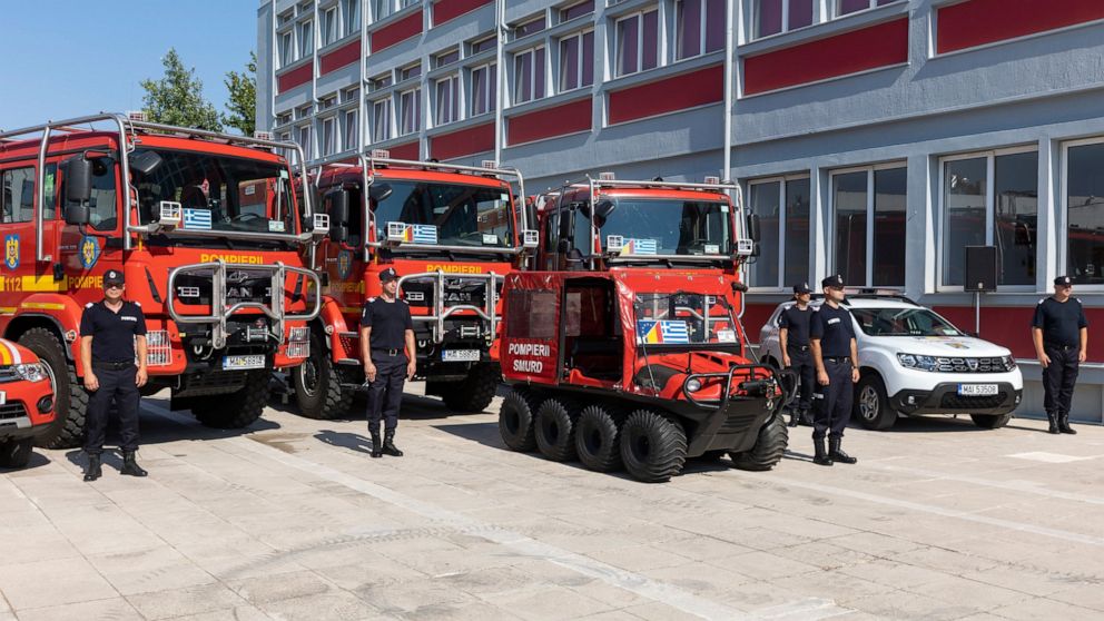 Romanian firefighters stand in front of fire engines during a ceremony, in Athens, on Saturday, July 2, 2022. Twenty eight Romanian firefighters, the first of more than 200 firefighters from other European countries that will help their Greek colleag