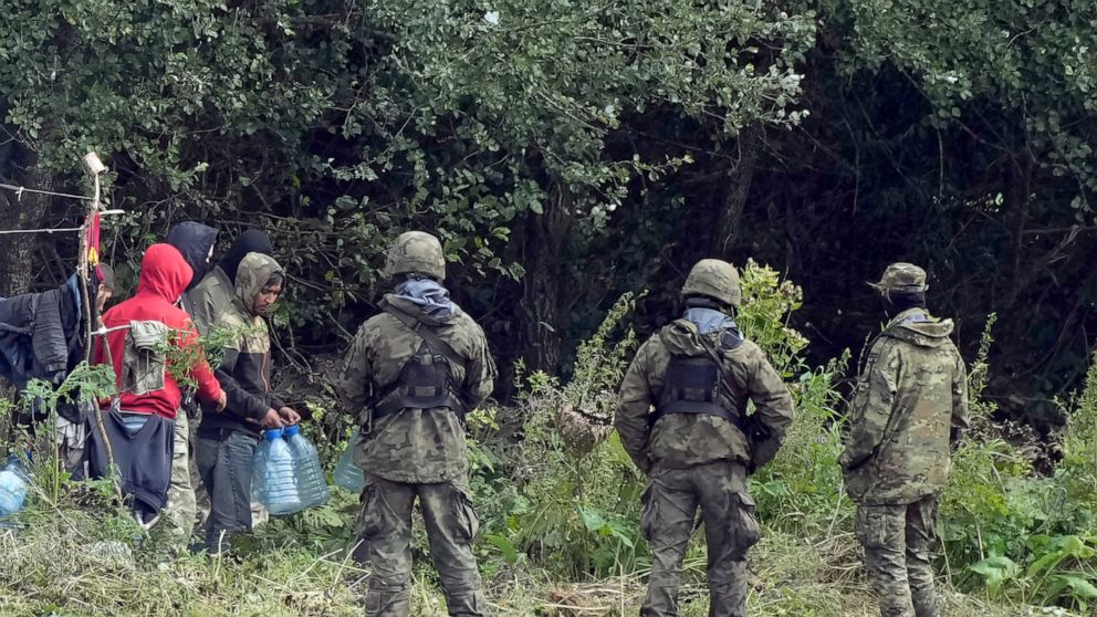 FILE - In this Sept. 1, 2021 file photo, migrants stuck along the Poland-Belarus border carry plastic water bottles as they are surrounded by Polish forces in Usnarz Gorny, Poland. Officials in Poland said Monday, Oct. 25, 2021, that two soldiers hav