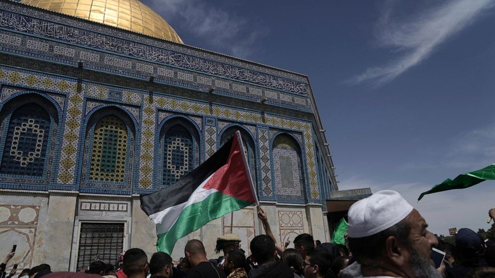 A worshipper waves the Palestinian flag after Friday prayers during the Muslim holy month of Ramadan, hours after Israeli police clashed with protesters at the Al Aqsa Mosque compound, in Jerusalem's Old City, Friday, April 22, 2022. (AP Photo/Mahmou