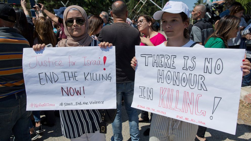 Two Palestinian women hold placards during a rally in front of the Prime Minister's office, in the West Bank city of Ramallah, Monday, Sept. 2. 2019. Hundreds of Palestinian women protested in front of the prime minister's office to demand an investi