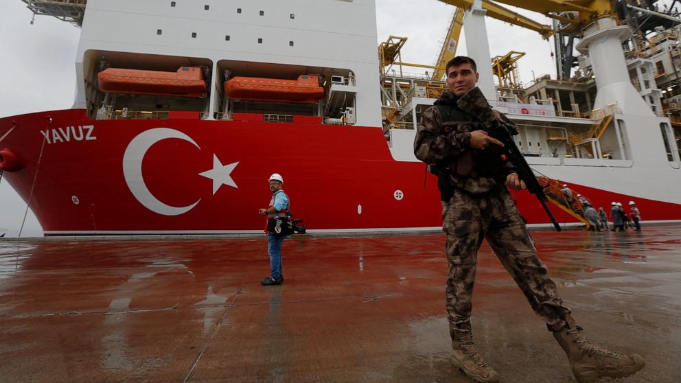 FILE - In this Thursday, June 20, 2019 file photo, a Turkish police officer patrols the dock, backdropped by the drilling ship 'Yavuz' to be dispatched to the Mediterranean, at the port of Dilovasi, outside Istanbul. The leaders of Greece, Israel and